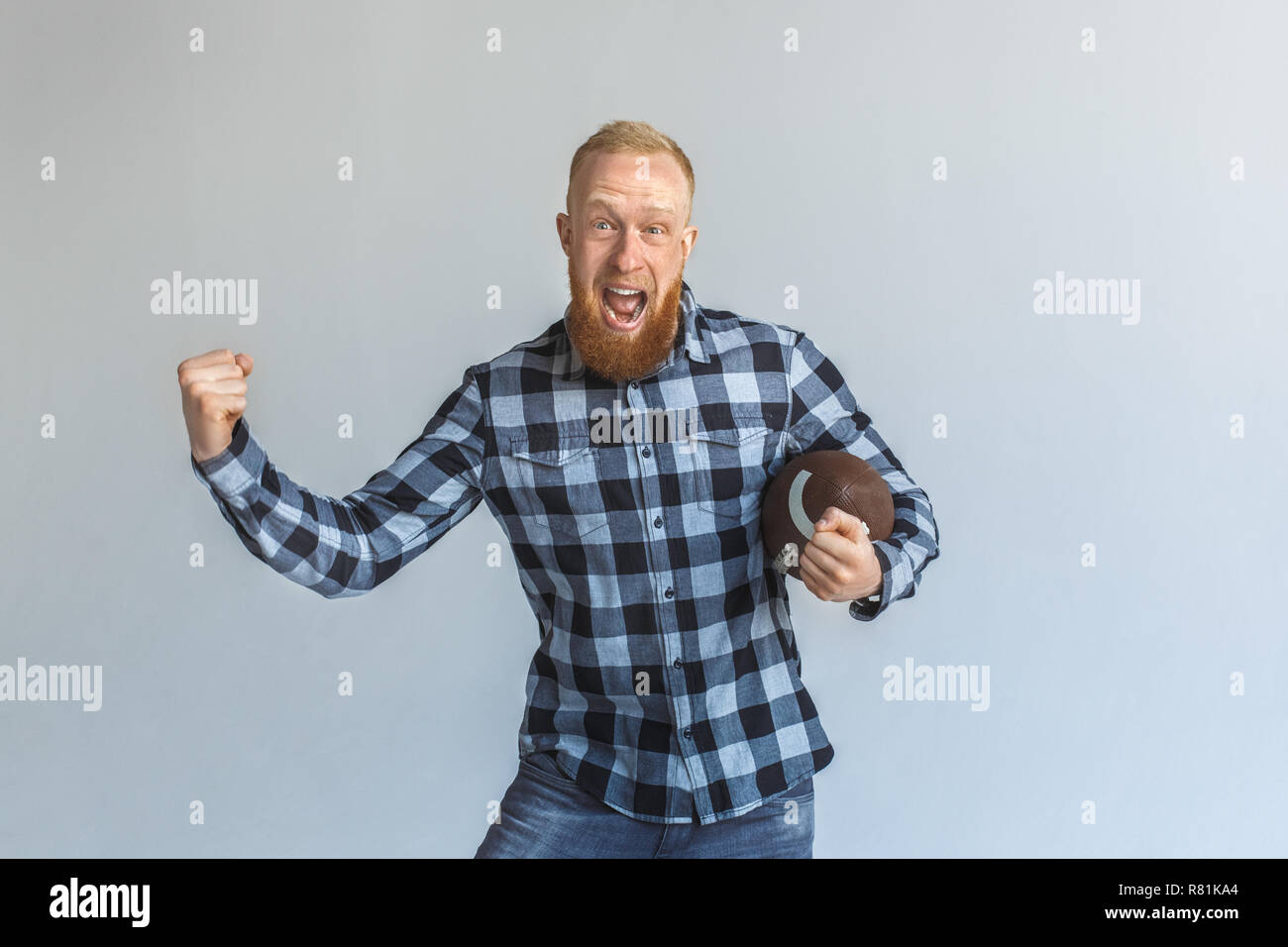 Lo spirito di squadra. Uomo maturo in piedi isolato su grigio con sfera gridando motivati Foto Stock
