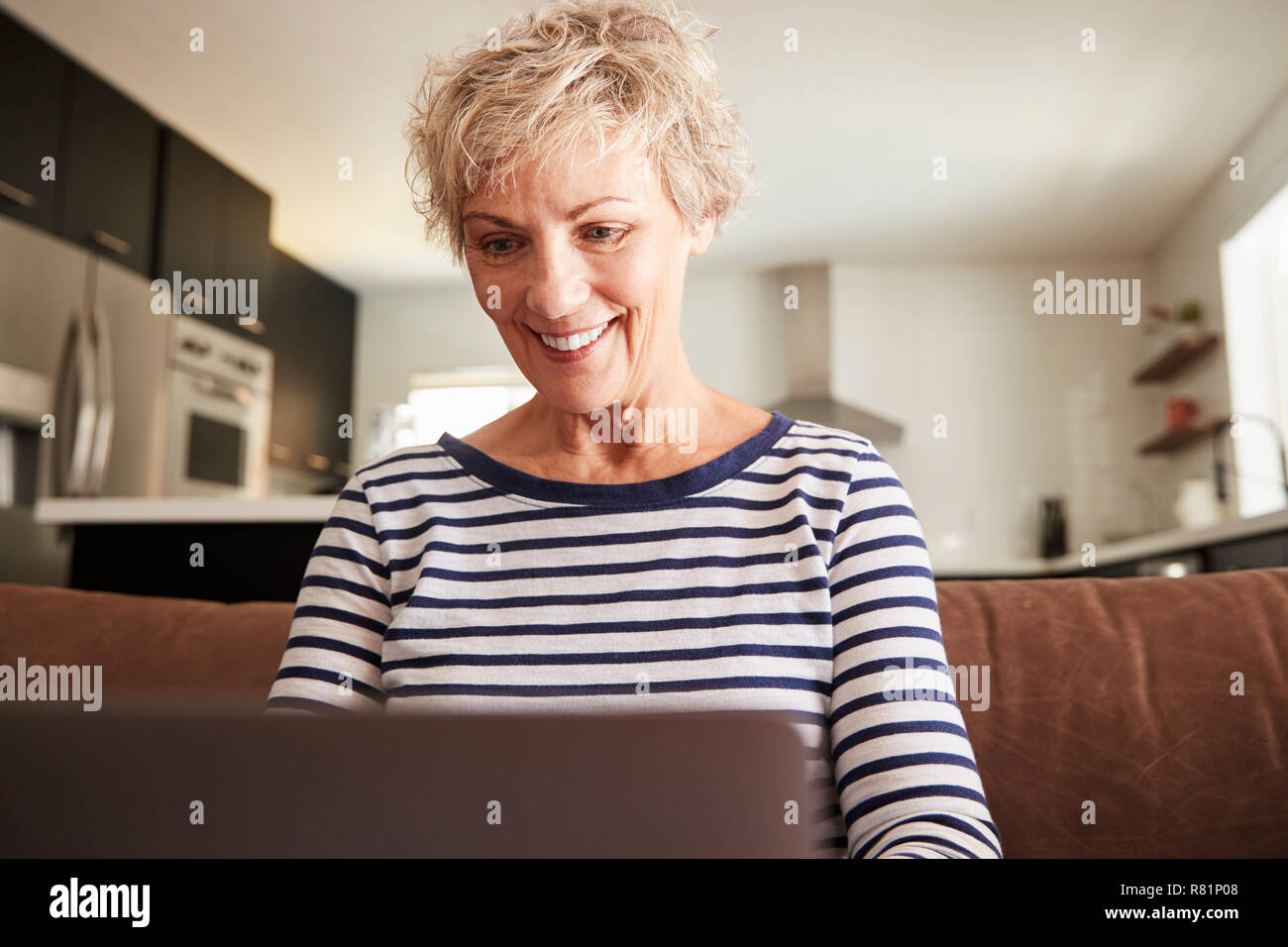 Senior donna bianca utilizzando computer portatile a casa, close up Foto Stock