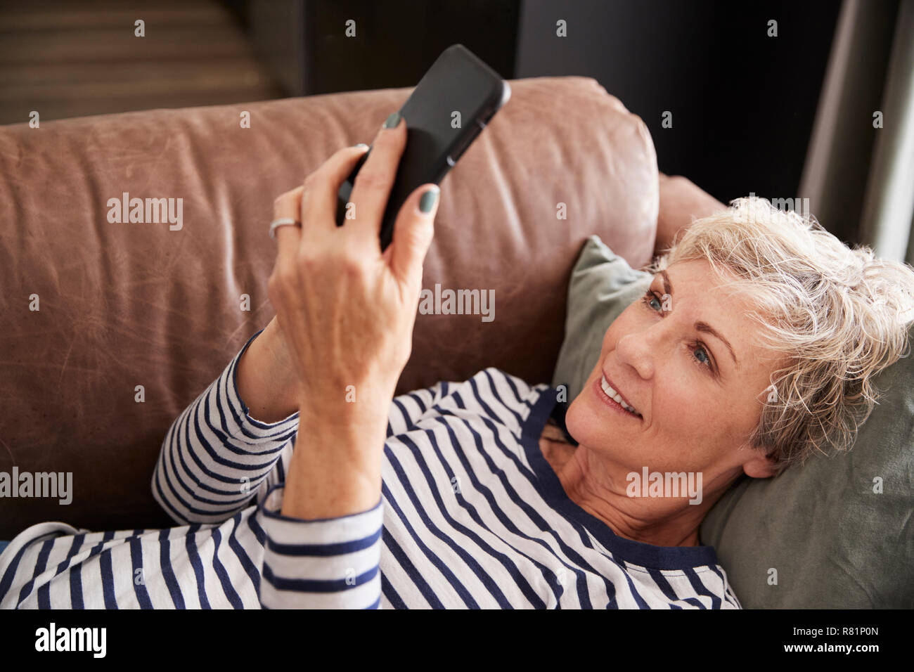 Senior donna sdraiata sul lettino usando il telefono, elevati close up Foto Stock