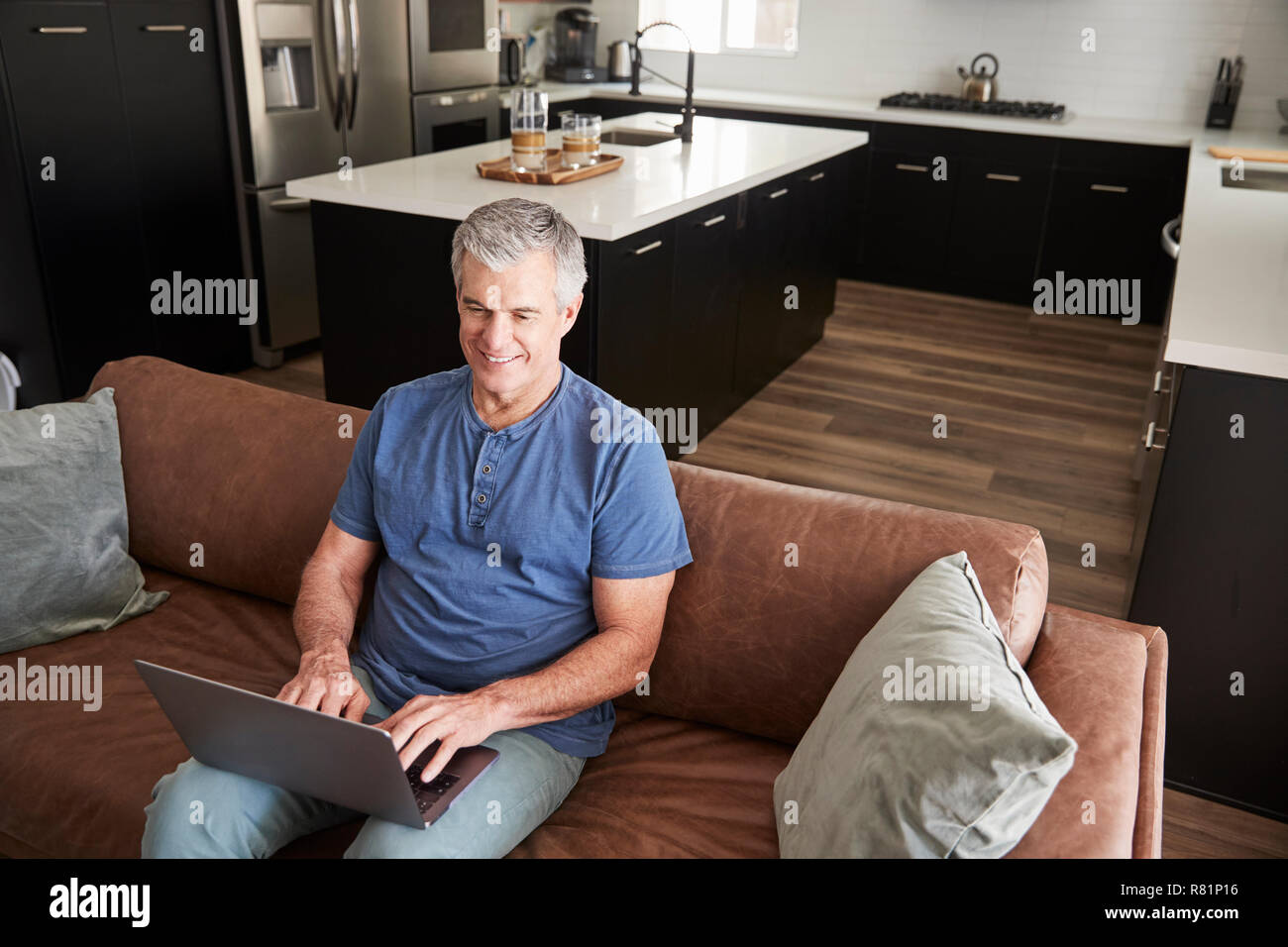 Senior bianco uomo seduto sul divano con laptop, vista in elevazione Foto Stock