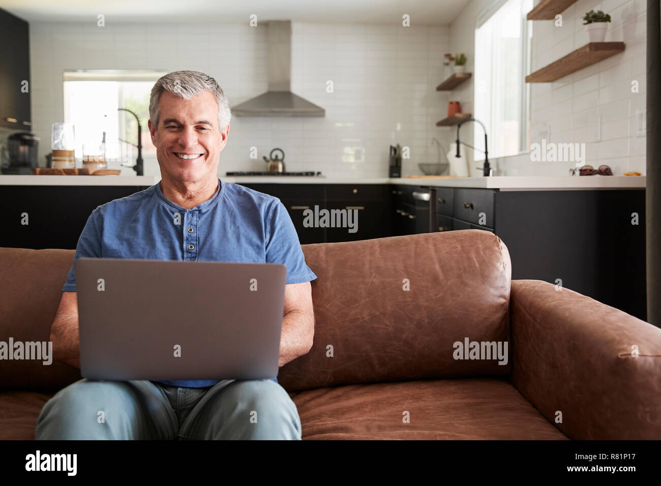 Senior bianco uomo seduto sul divano di casa utilizzando laptop Foto Stock