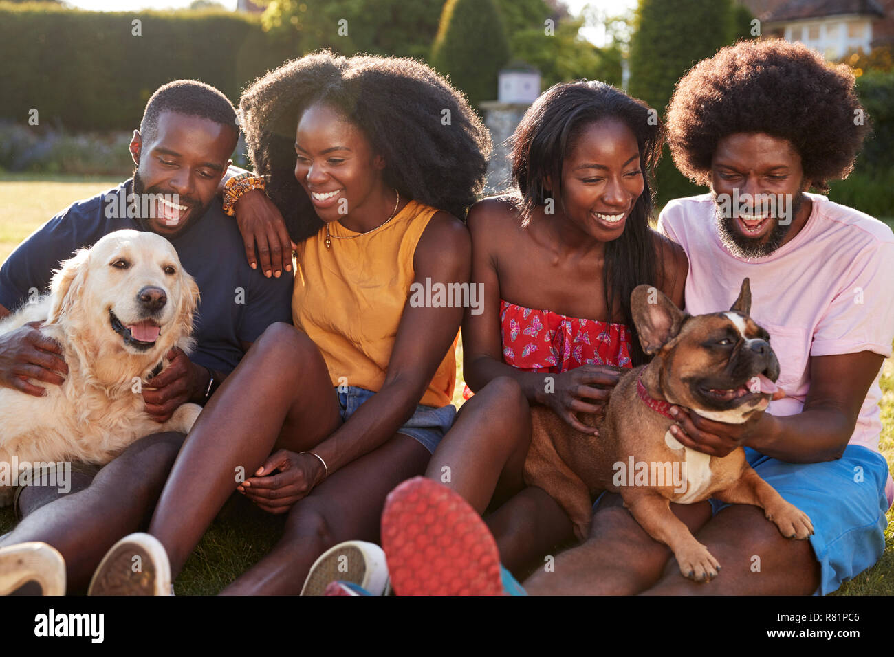 Due coppie con cani seduti in un giardino Foto Stock
