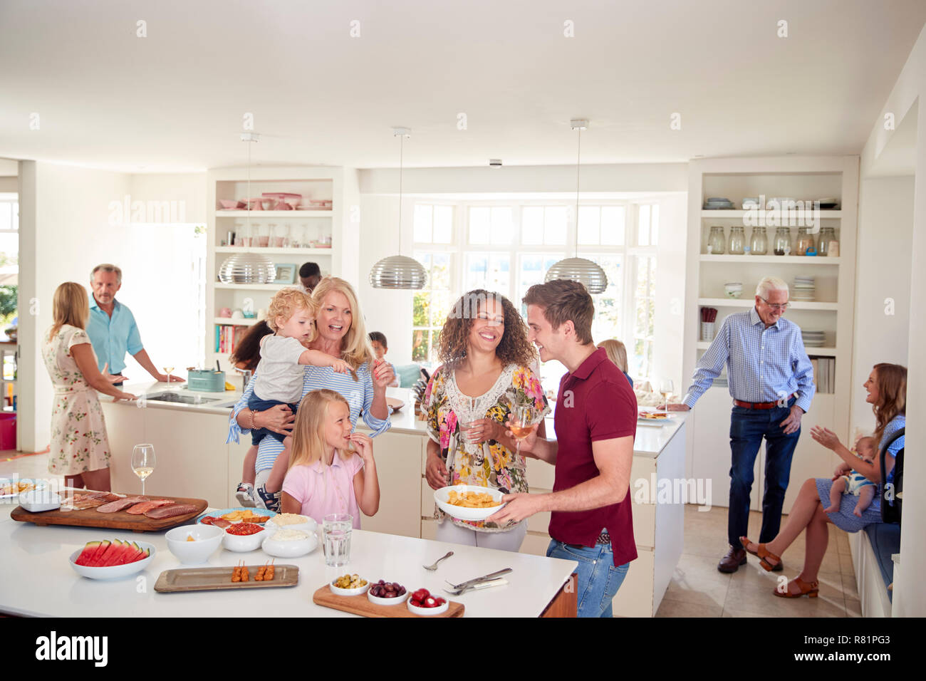 Multi-Generation la famiglia e gli amici raccogliendo in cucina per la Festa Foto Stock