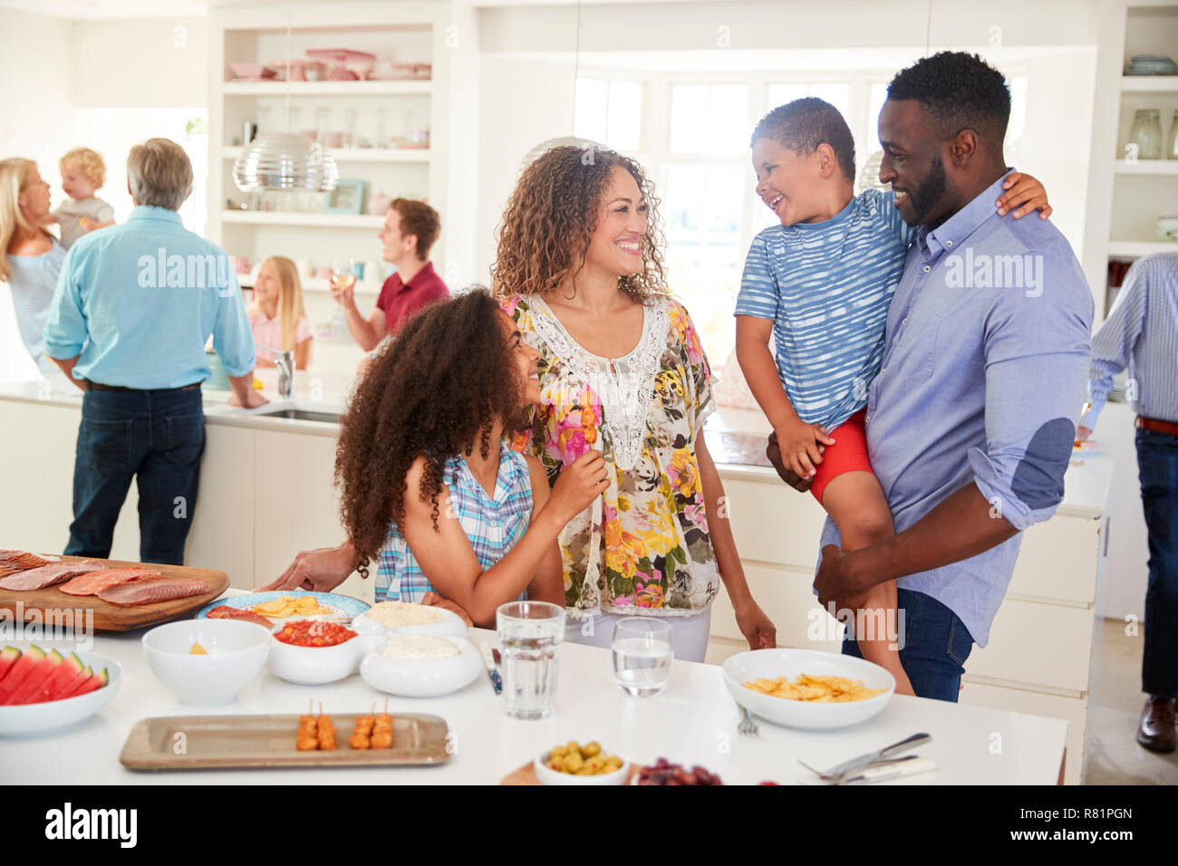 Multi-Generation la famiglia e gli amici raccogliendo in cucina per la Festa Foto Stock