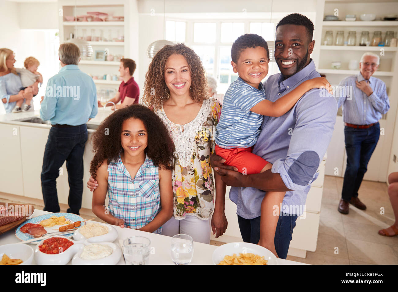 Ritratto di famiglia con amici in cucina per Multi-Generation Party Foto Stock