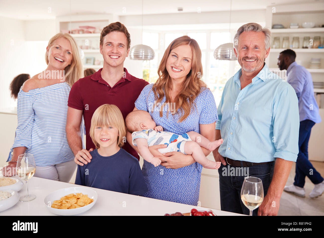 Ritratto di Multi-Generation la famiglia e gli amici raccogliendo in cucina per la Festa Foto Stock
