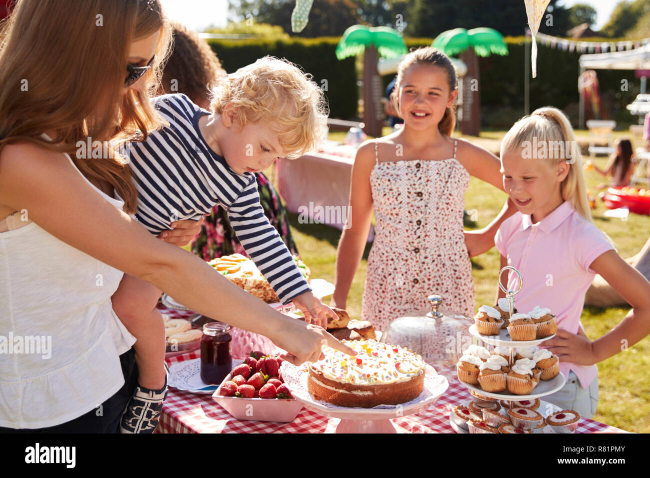 I bambini che serve sulla torta di stallo occupato al giardino estivo Fete Foto Stock