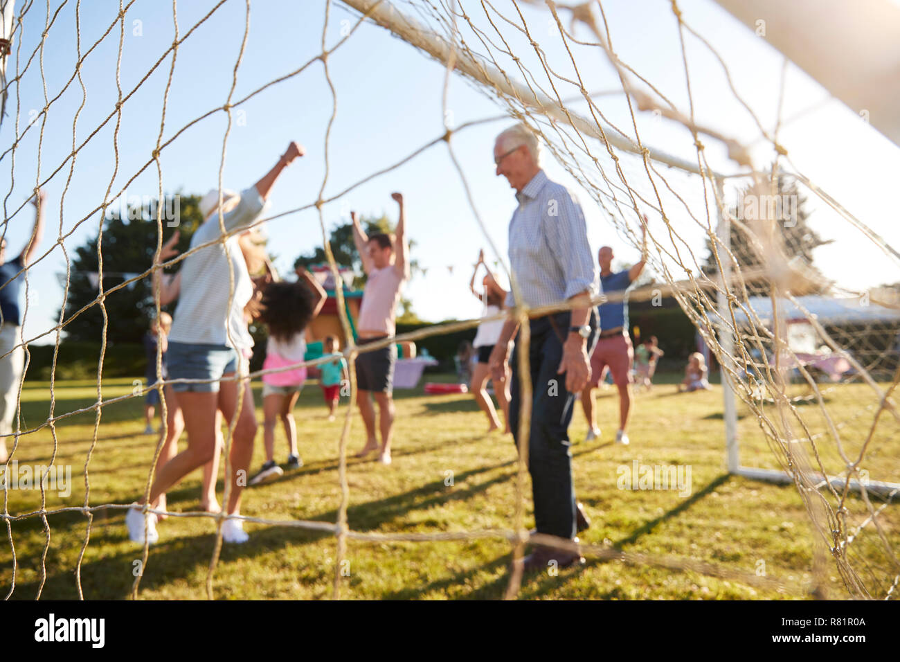 Bambini che giocano una partita di calcio con gli adulti al giardino estivo Fete Foto Stock