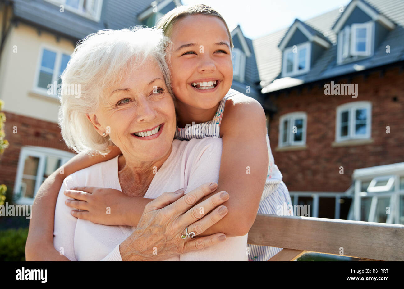 La nipote abbracciando la nonna sul banco durante la visita alla casa di riposo Foto Stock