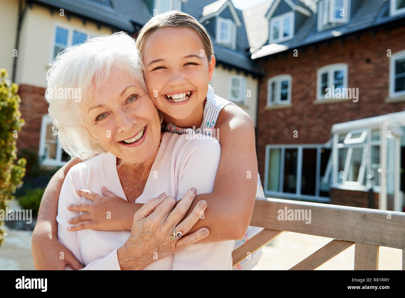 Ritratto del nipote abbracciando la nonna sul banco durante la visita alla casa di riposo Foto Stock