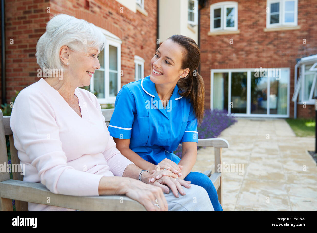 Senior donna seduta sul banco di lavoro e parlare con un infermiere in casa di riposo Foto Stock