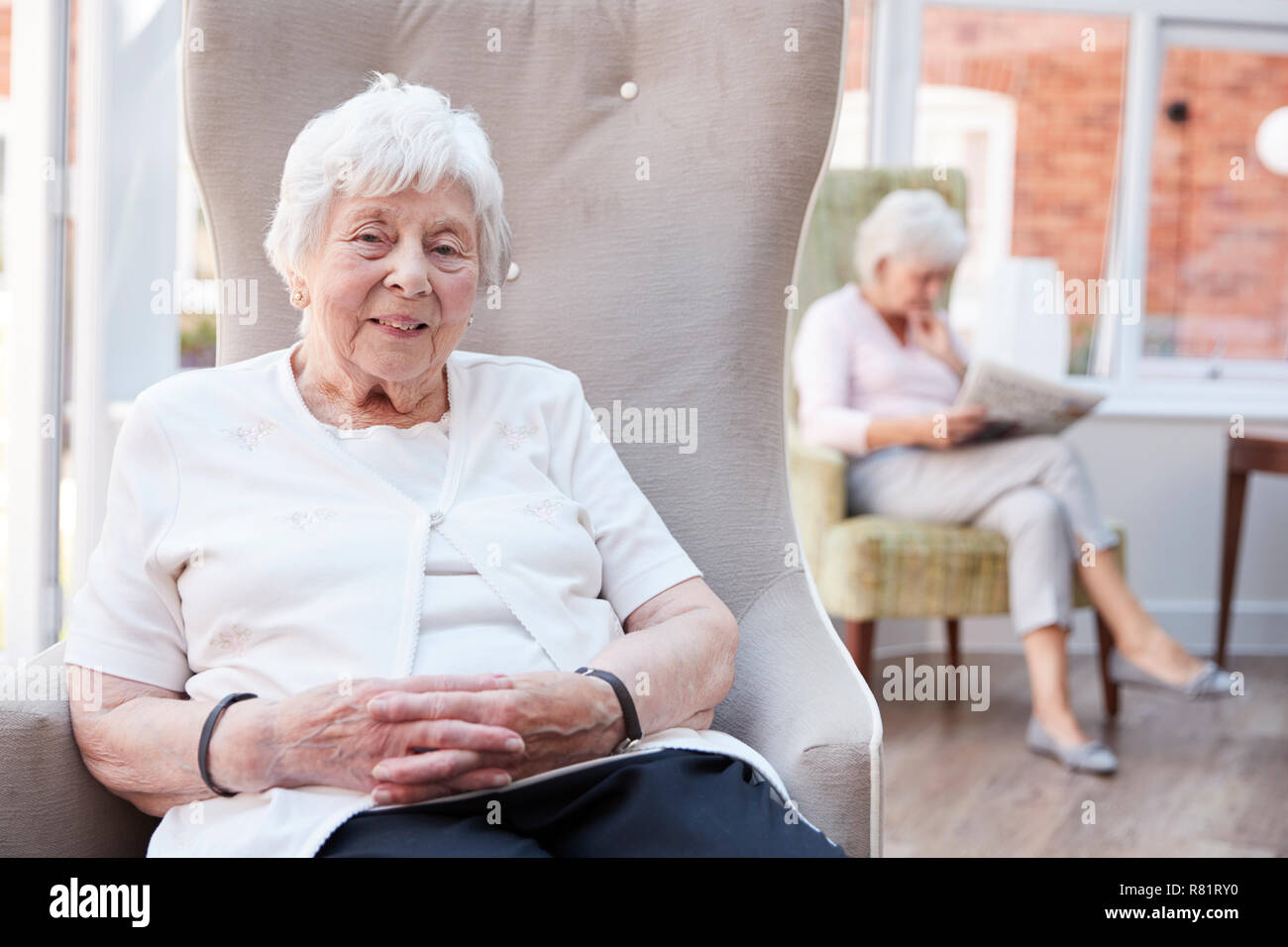Ritratto di donna Senior seduto in poltrona nel salotto di casa di riposo Foto Stock