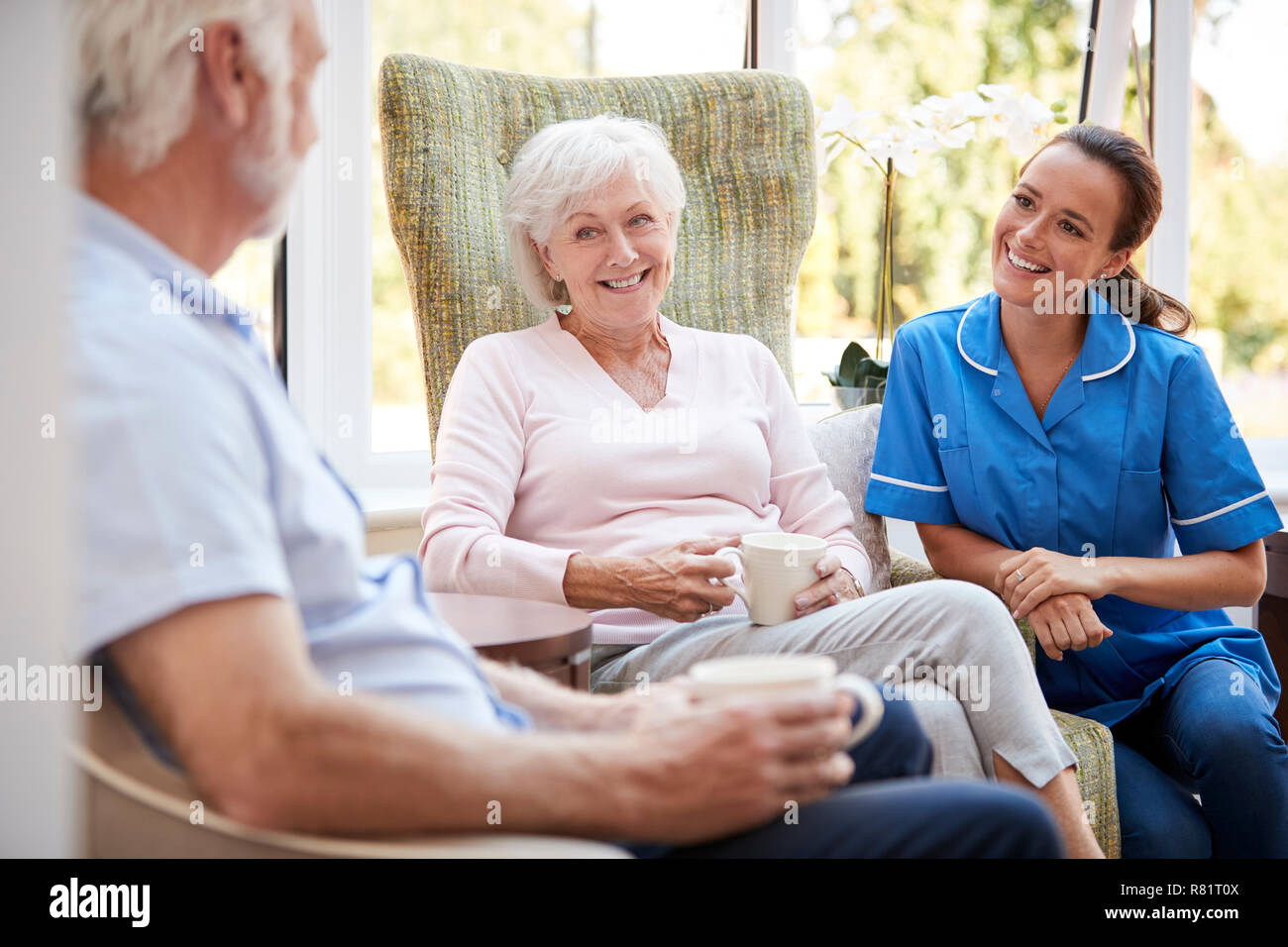 Coppia senior seduto in poltrona e parlare con un infermiere in casa di riposo Foto Stock