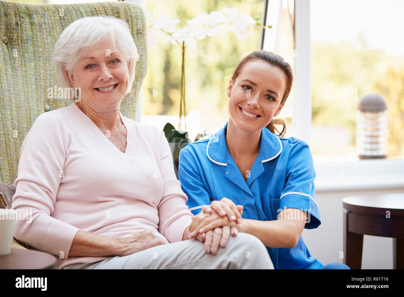 Ritratto di donna Senior seduto in poltrona con un infermiere in casa di riposo Foto Stock