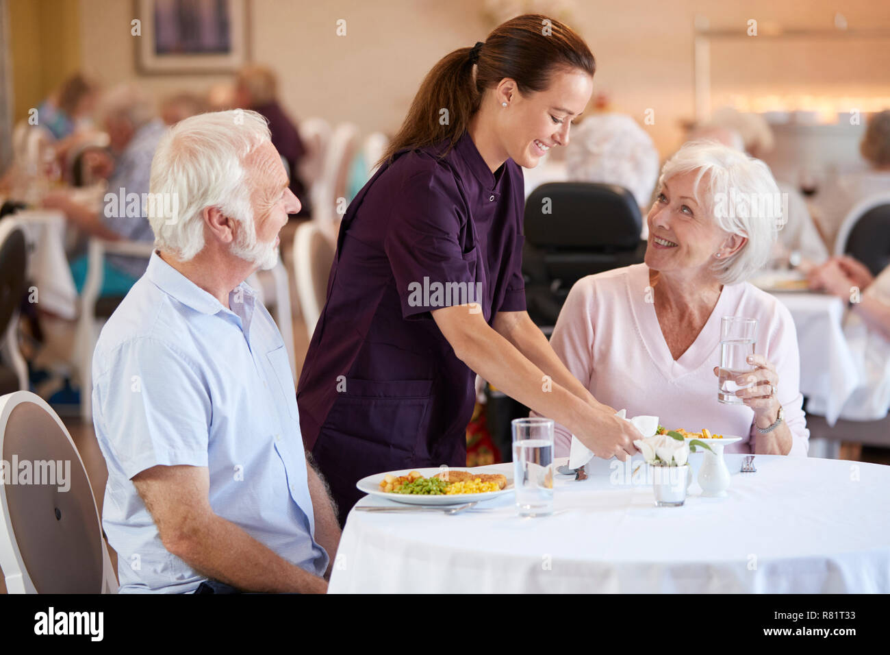 Coppia senior di essere servito con pasto dal caregiver nella sala da pranzo della casa di riposo Foto Stock