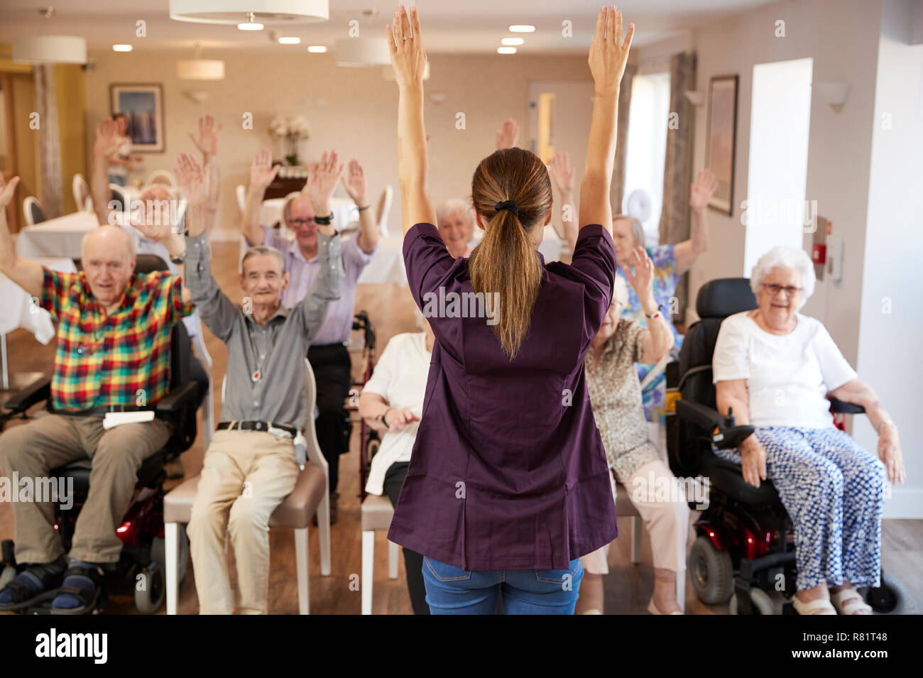 Accompagnatore Gruppo leader di anziani nella classe di Fitness in casa di riposo Foto Stock