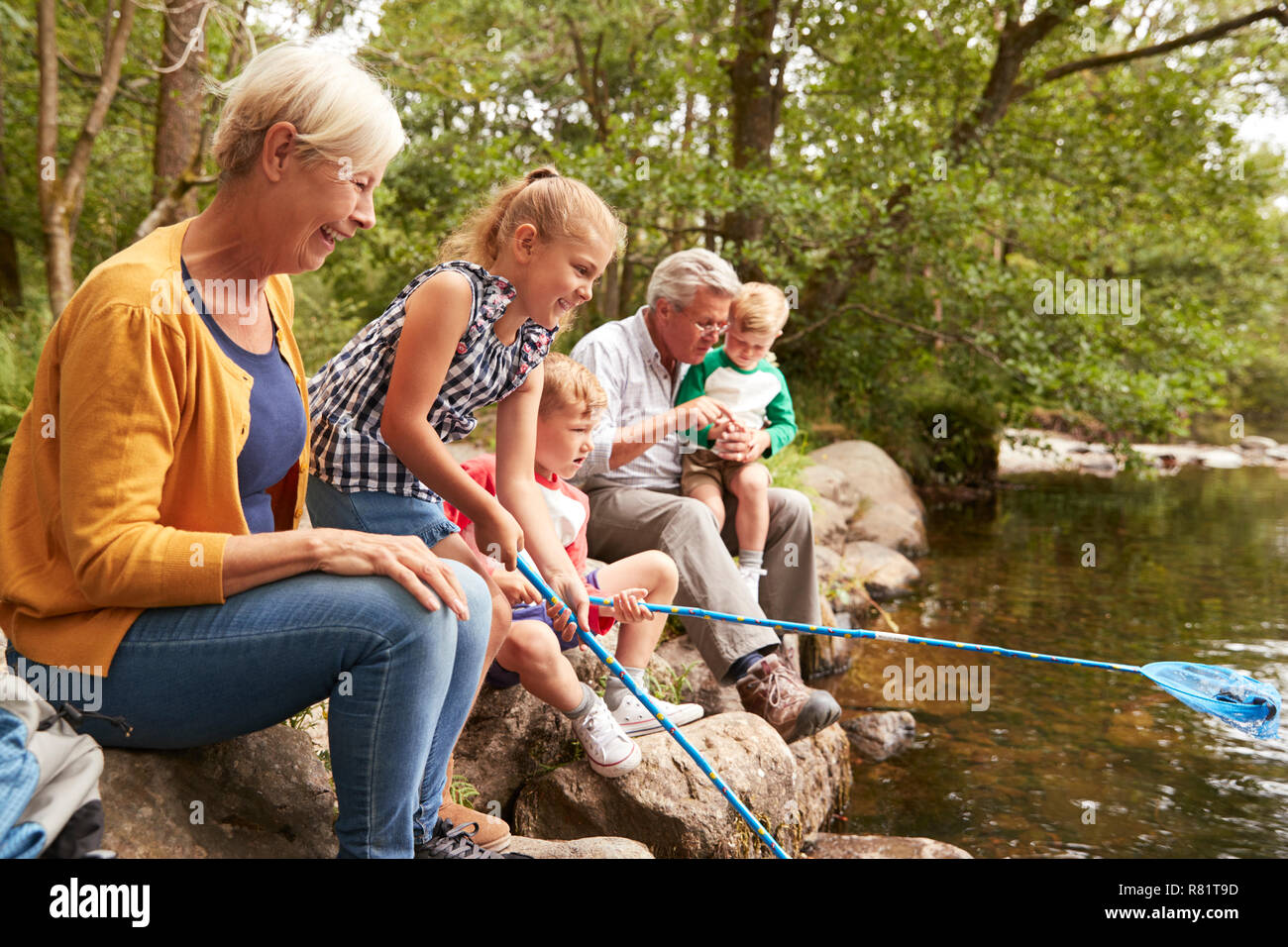Nonni con i nipoti la pesca con le reti nel fiume in UK Lake District Foto Stock
