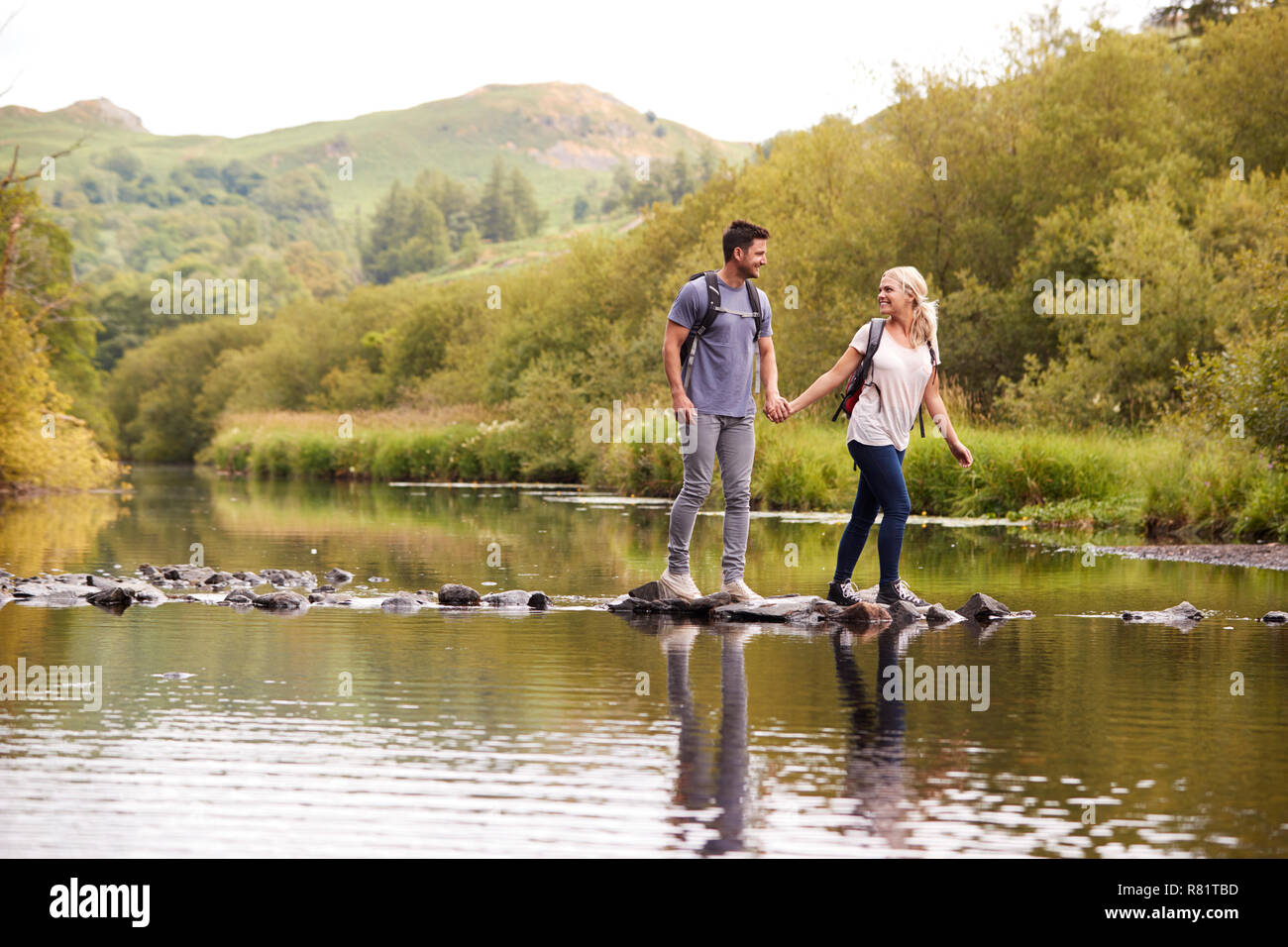 Giovane Varcando il fiume mentre escursionismo in UK Lake District Foto Stock