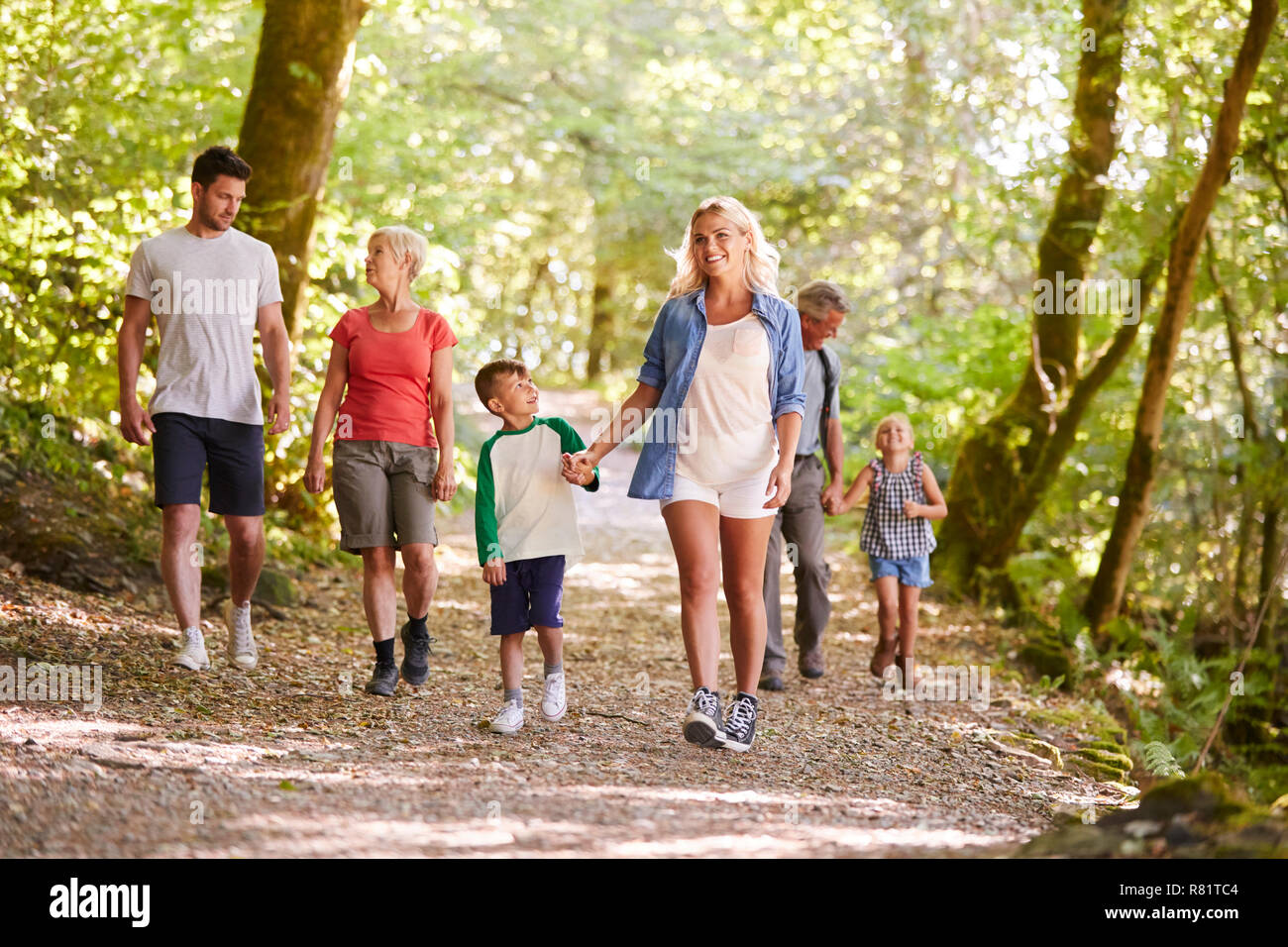 Generazione Multi Family godendo a piedi lungo il sentiero del bosco insieme Foto Stock