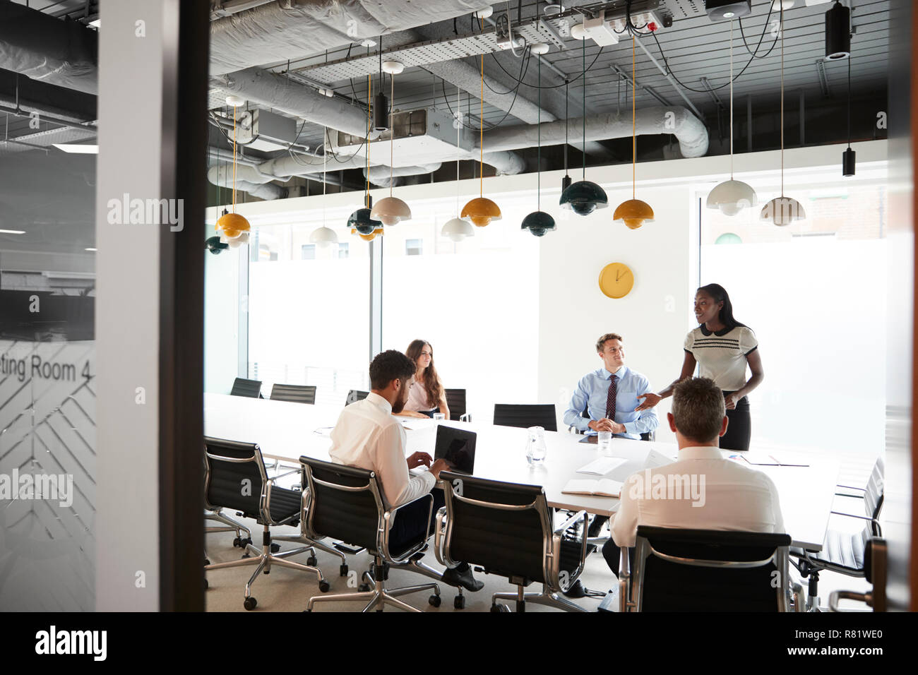 Imprenditrice dando presentazione nella sala consiliare visto attraverso la Sala Riunioni porta Foto Stock