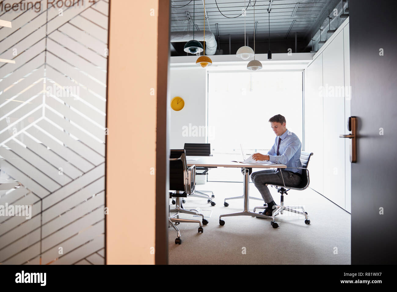 Imprenditore lavora su computer portatile al Tavolo per riunioni visto attraverso la Sala Riunioni porta Foto Stock