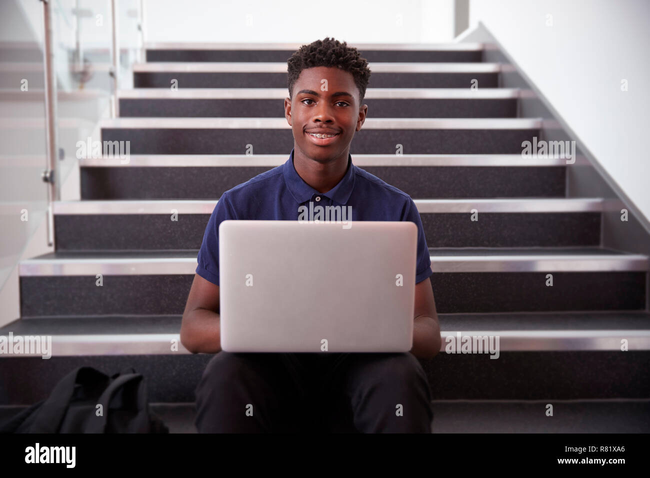 Ritratto maschile di alta scuola studente seduto sulla scalinata e utilizzando computer portatile Foto Stock