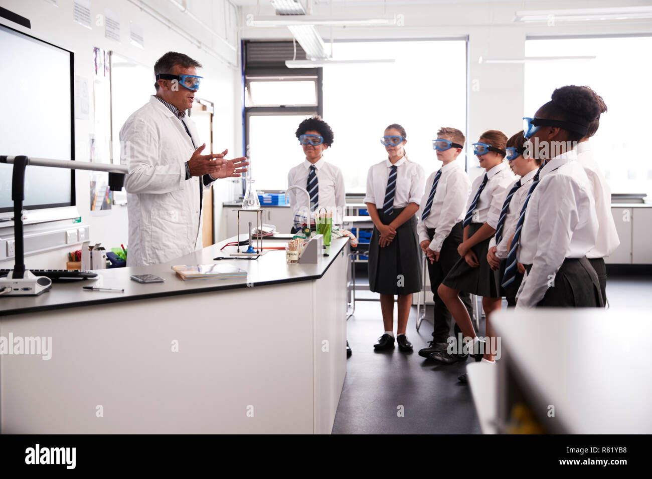Maschio della High School Tutor insegnamento di alta scuola gli studenti indossano uniformi nella Classe di Scienze Foto Stock