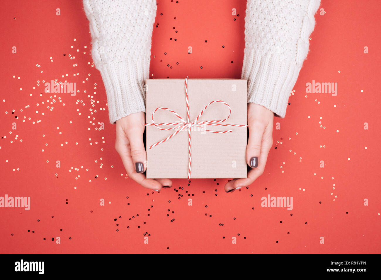 Confezione regalo con fiocco in donna con le mani in mano. Coralli viventi - Colore dell'anno 2019. Foto Stock