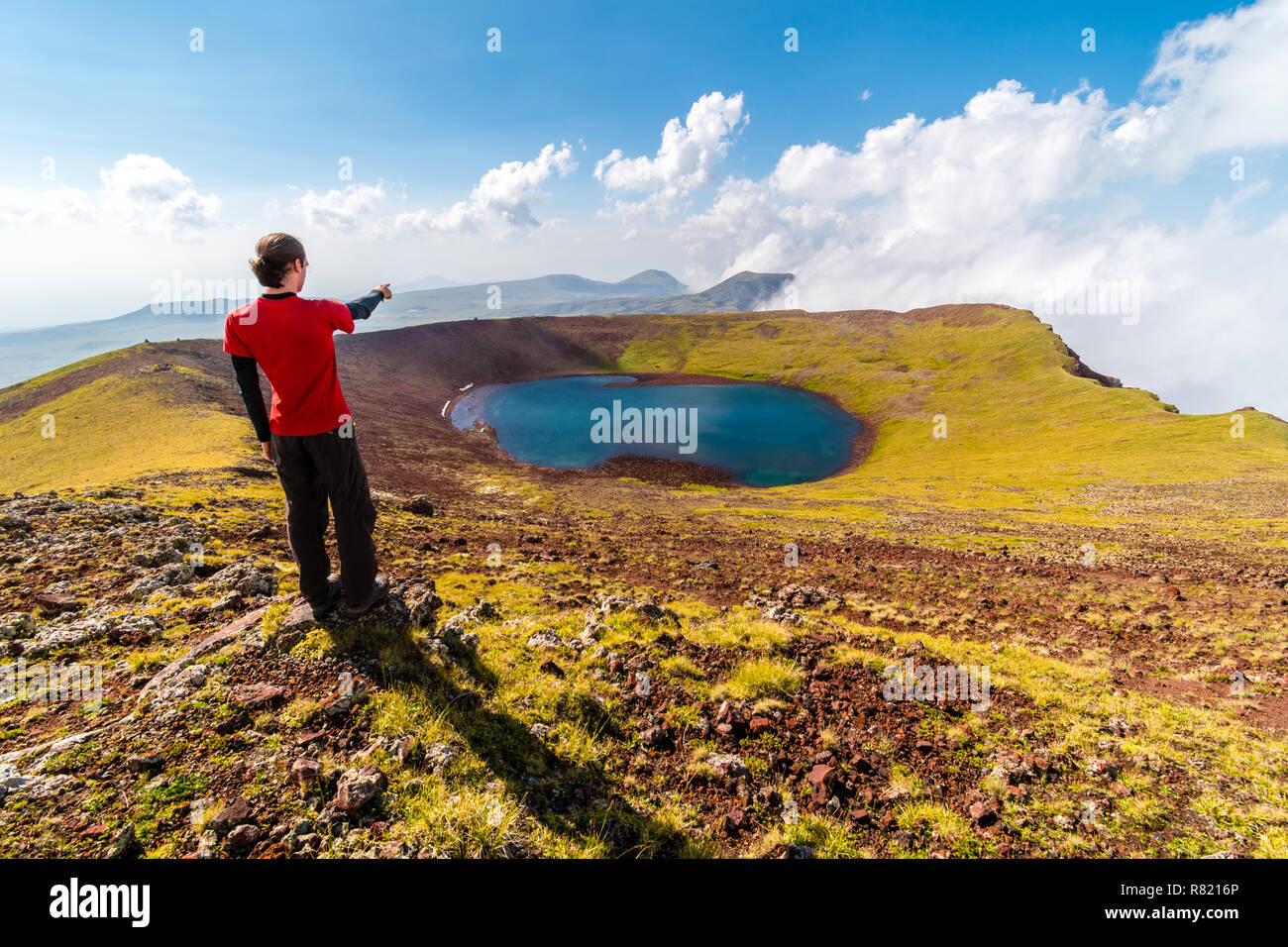 Uomo al vertice del vulcano Azhdahak guardando il cratere del lago, Geghama mountains, Armenia Foto Stock