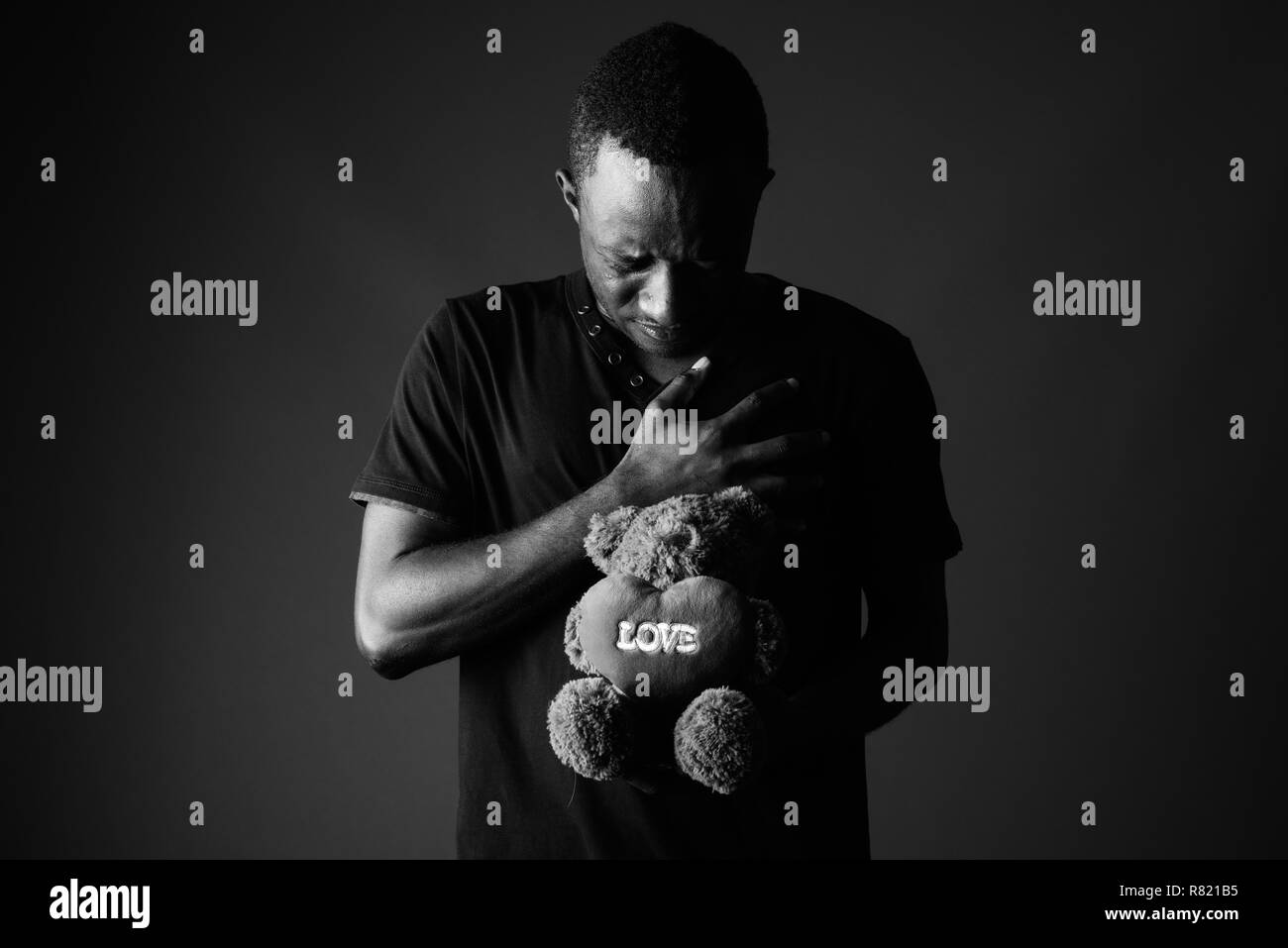 Triste giovane africano con Teddy bear e segno di amore del testo in bianco e nero Foto Stock