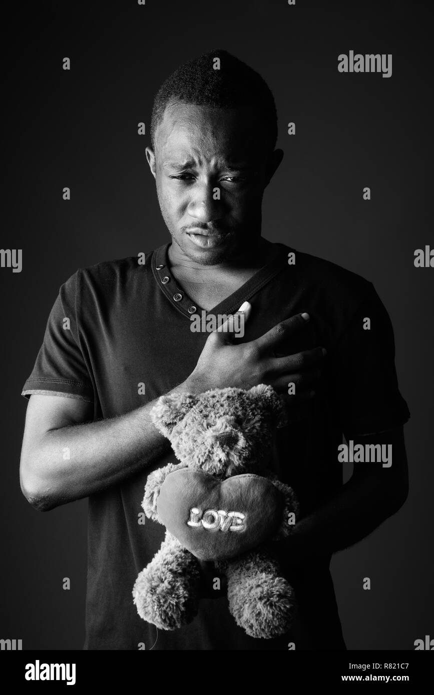 Triste giovane africano con Teddy bear e segno di amore del testo in bianco e nero Foto Stock