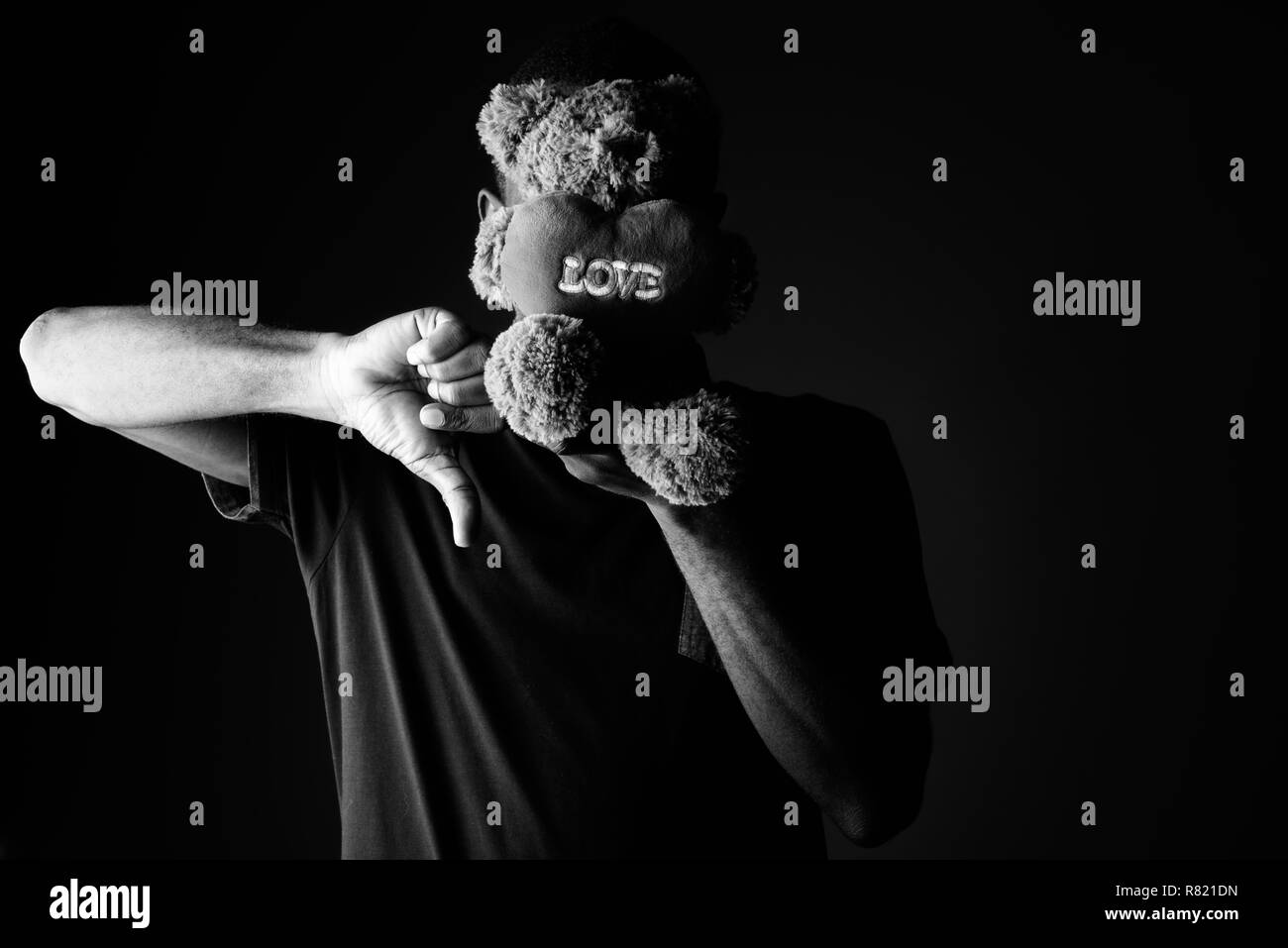 Triste giovane africano con Teddy bear e segno di amore il testo dando il pollice verso il basso Foto Stock
