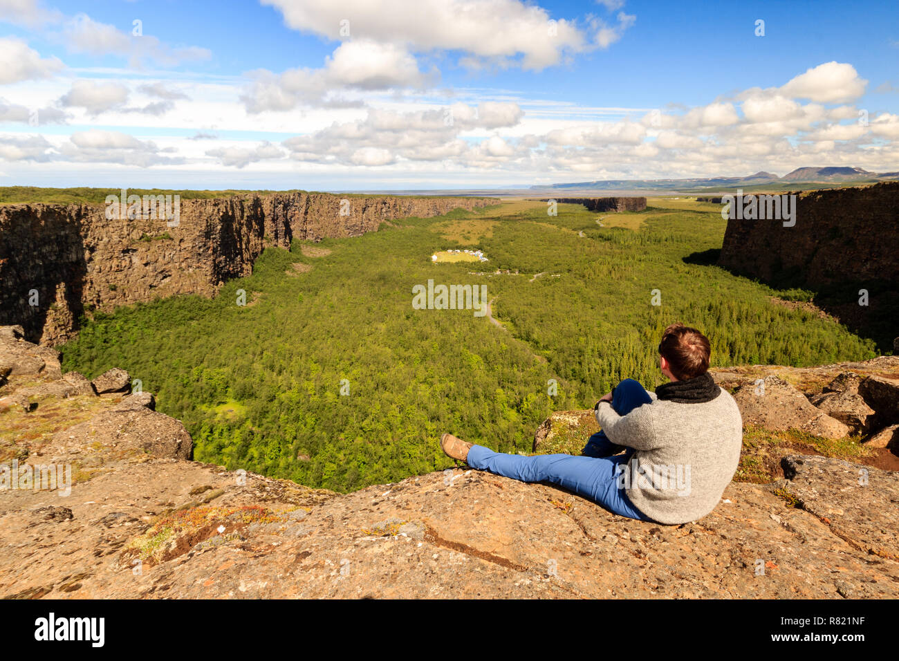 Escursionista sul bordo del canyon Asbyrgi in Islanda godendo la vista / Wanderer an der Kante der Asbyrgi Schlucht a isola Foto Stock