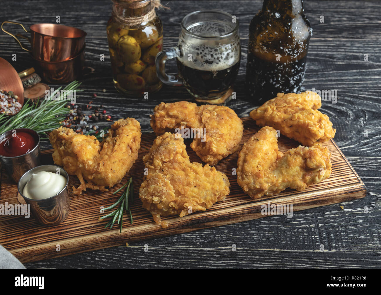 Alette di pollo fritte in pastella, rosso e salsa bianca su di una superficie scura Foto Stock