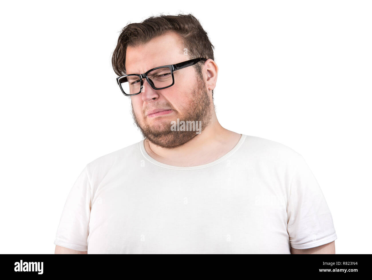 Giovane uomo barbuto in bicchieri accigliata del cattivo odore cercando profondamente dispiaciuto su sfondo bianco Foto Stock