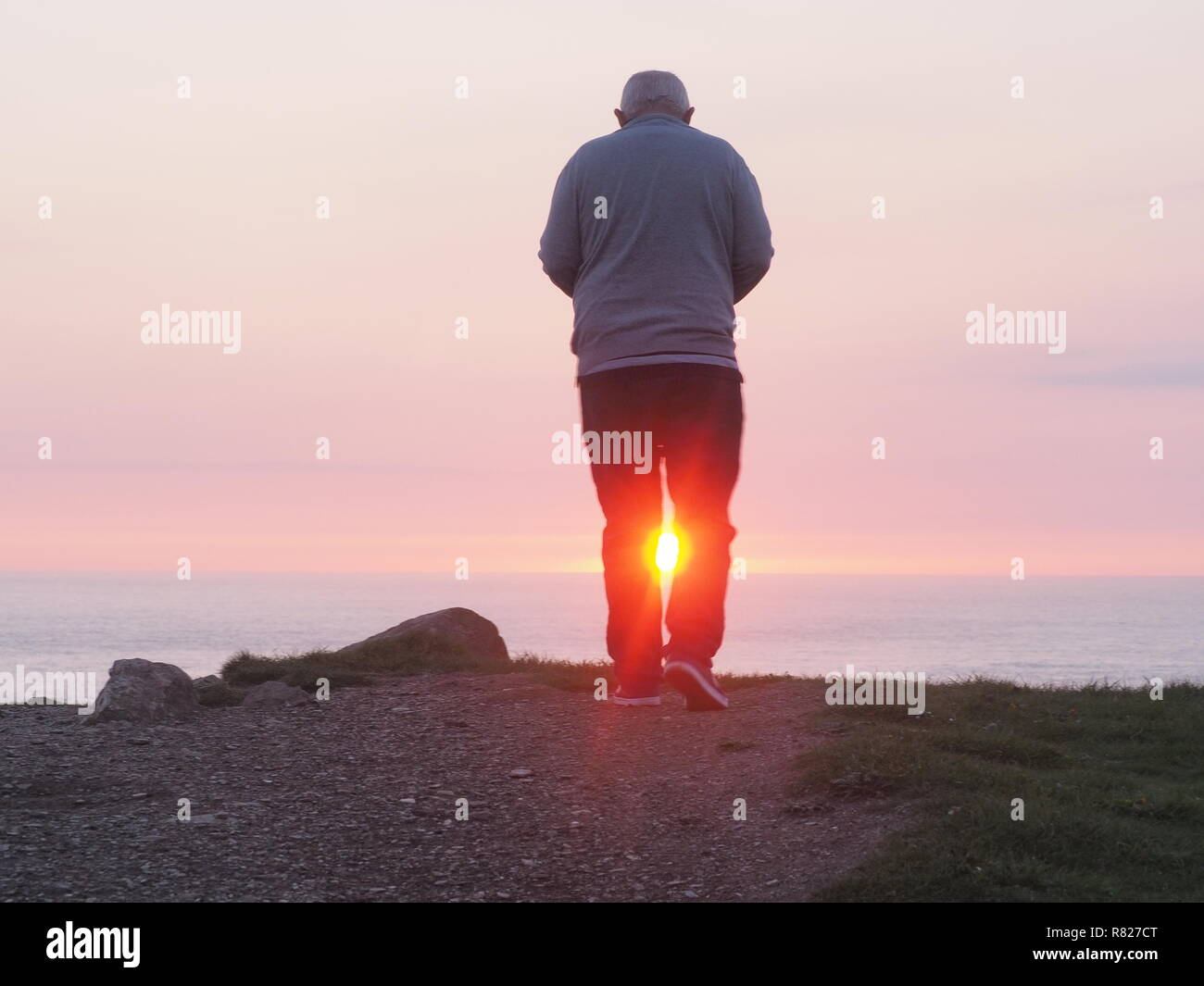 Uomo anziano incorniciata dal tramonto vista posteriore Foto Stock