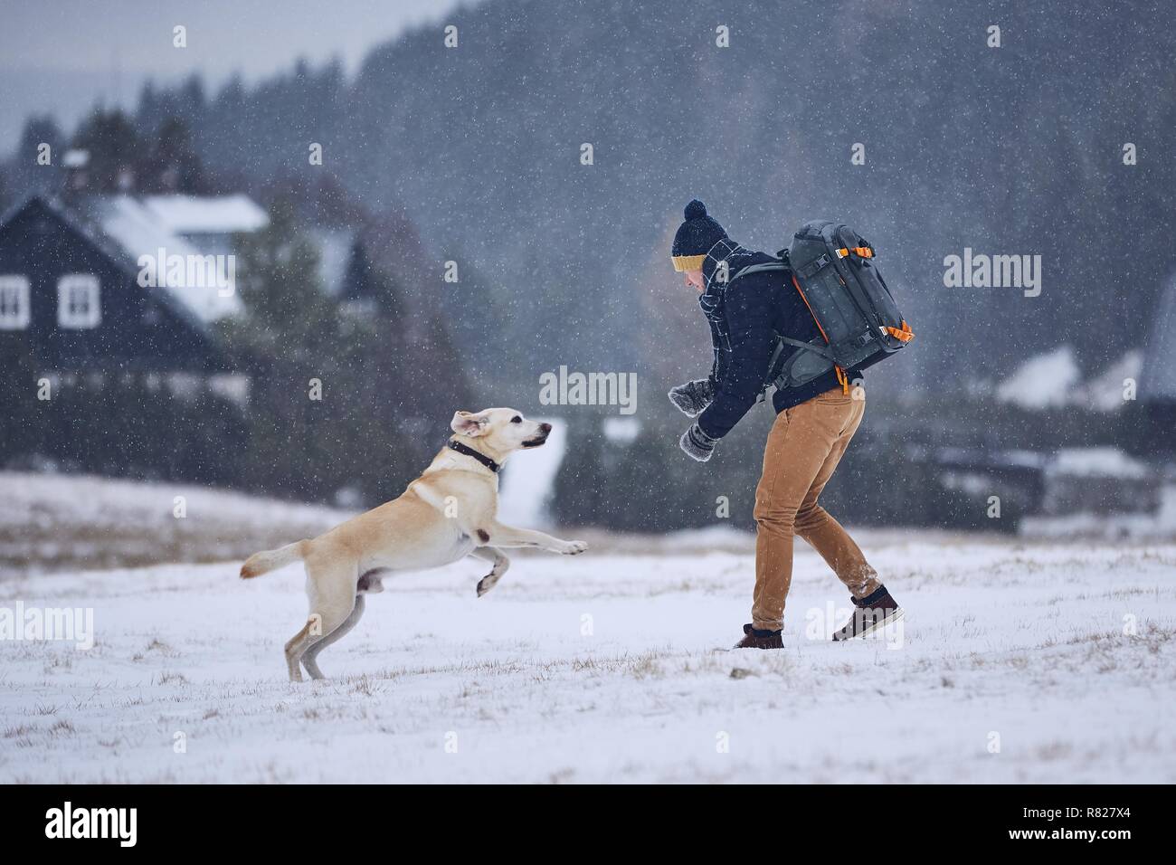 L'amicizia tra pet proprietario e il suo cane. Giovane uomo giocando con il labrador retriever nel paesaggio invernale. Montagne di Jizera, Repubblica Ceca Foto Stock