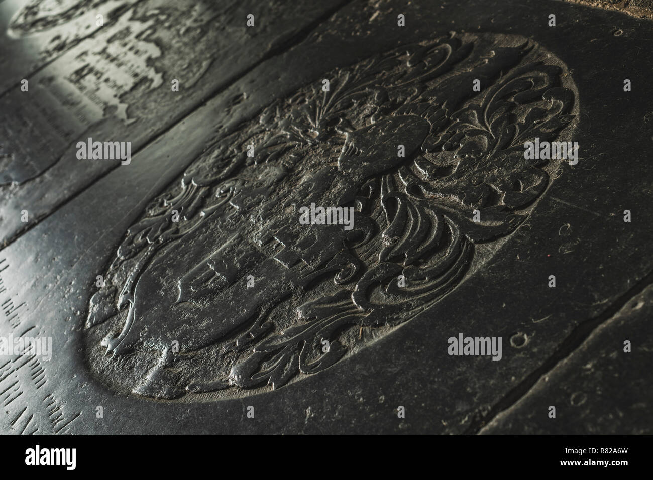 Un weathered marmo nero Ledgerstone prevista nel pavimento della chiesa vicino alla cappella della Madonna a Wells nel Somerset. Foto Stock