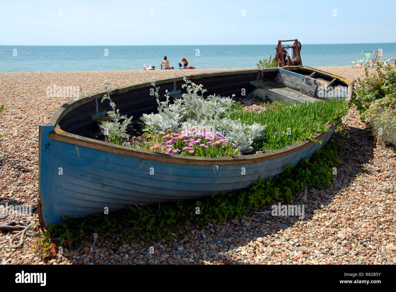 Vecchio dinghy sulla spiaggia di Brighton, East Sussex, Inghilterra e decorate con una varietà di attrattive piante Foto Stock