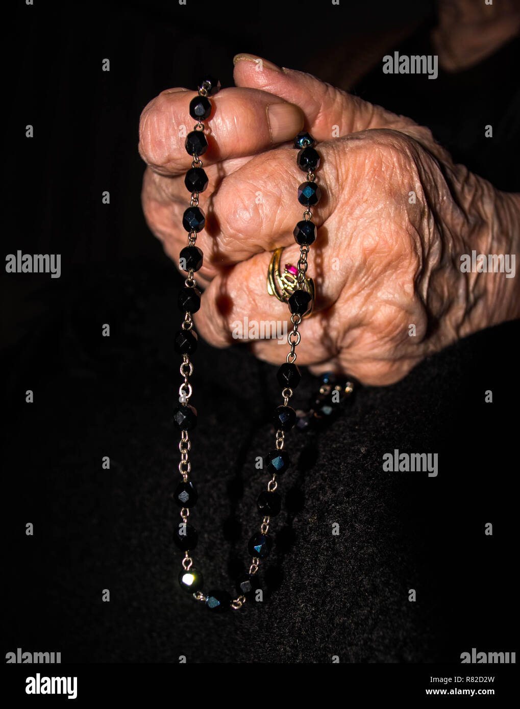 Pregando le mani con il rosario Foto Stock