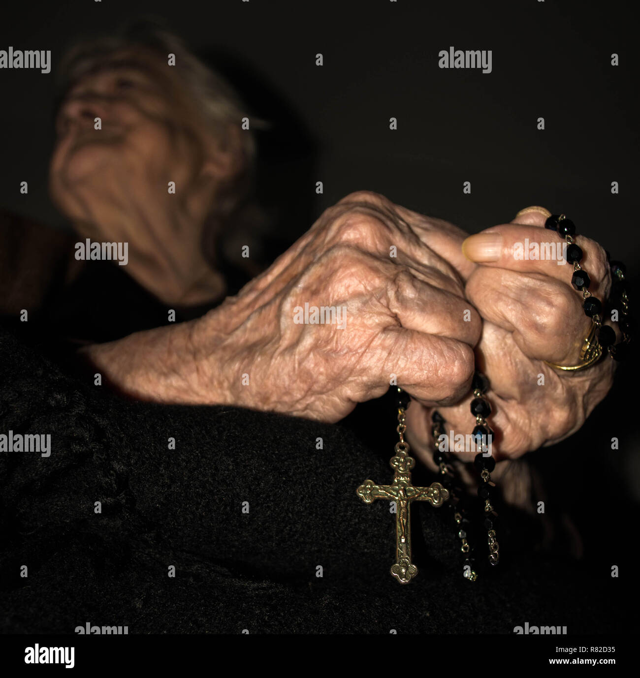 Pregando le mani con il rosario Foto Stock