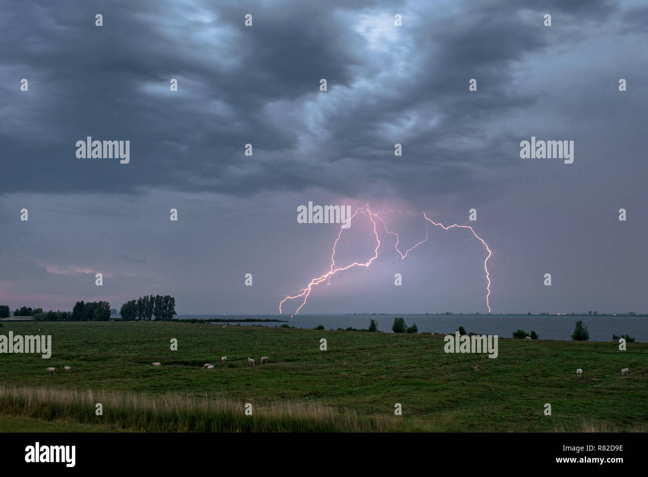 Il fulmine colpisce più volte in acqua sotto un cielo drammatico. Fotografato durante un inseguimento di un temporale oltre a sudovest nei Paesi Bassi. Foto Stock