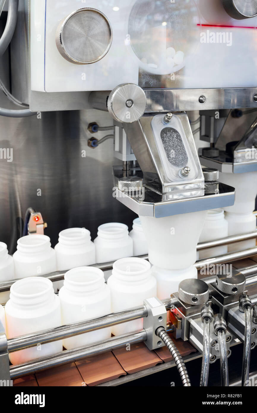 Industria farmaceutica, medicina pillole sono il riempimento della bottiglia di plastica sulla linea di produzione trasportatore di macchina presso il medico di fabbrica. Il fuoco selettivo. Foto Stock