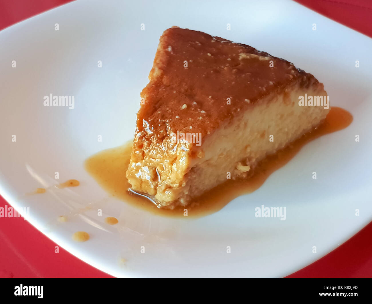 Un gustoso pezzo di pudding con sciroppo di zucchero su una piastra bianca Foto Stock