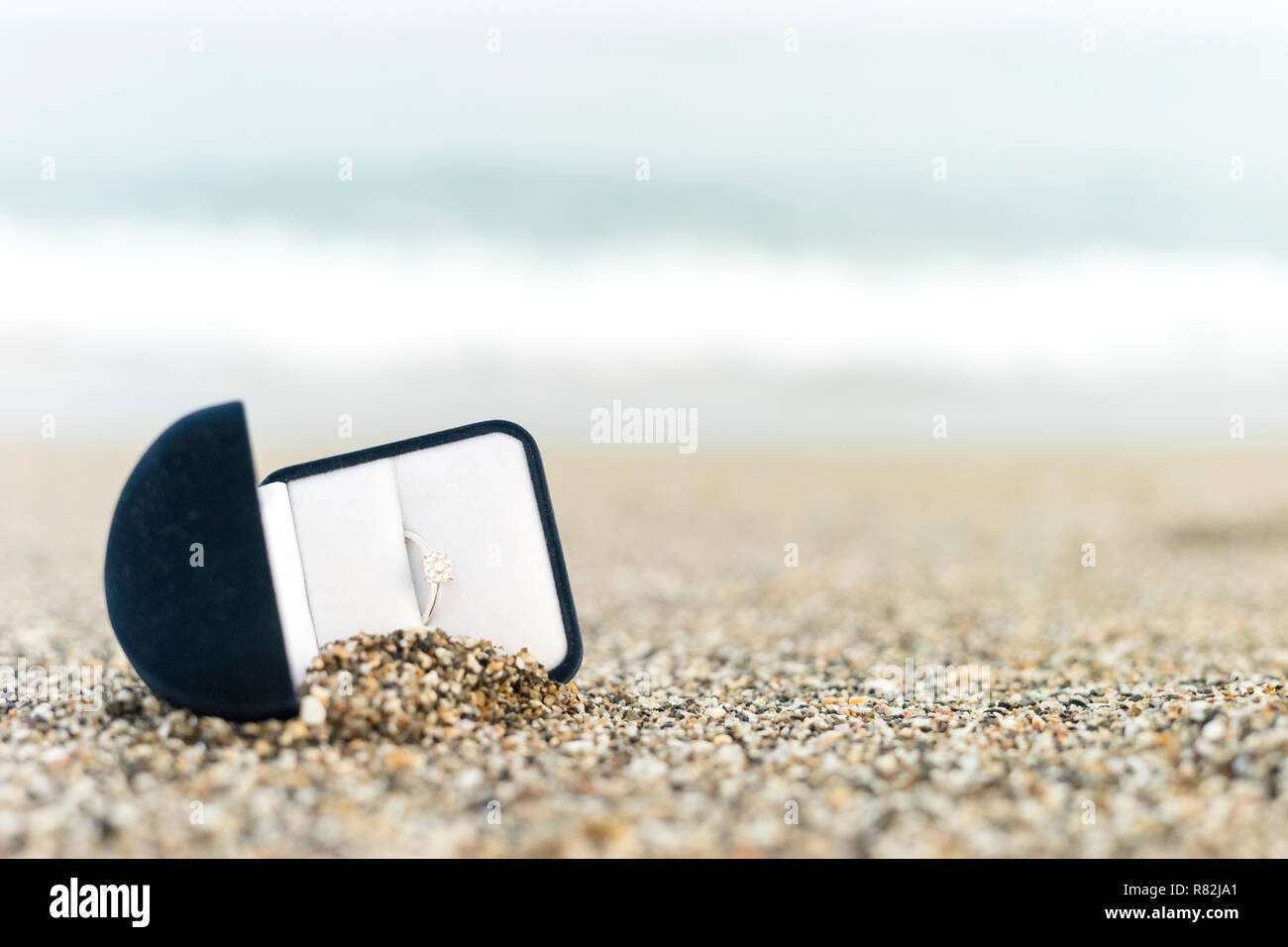 Anello di fidanzamento con diamante in elegante scatola sulla spiaggia Foto Stock