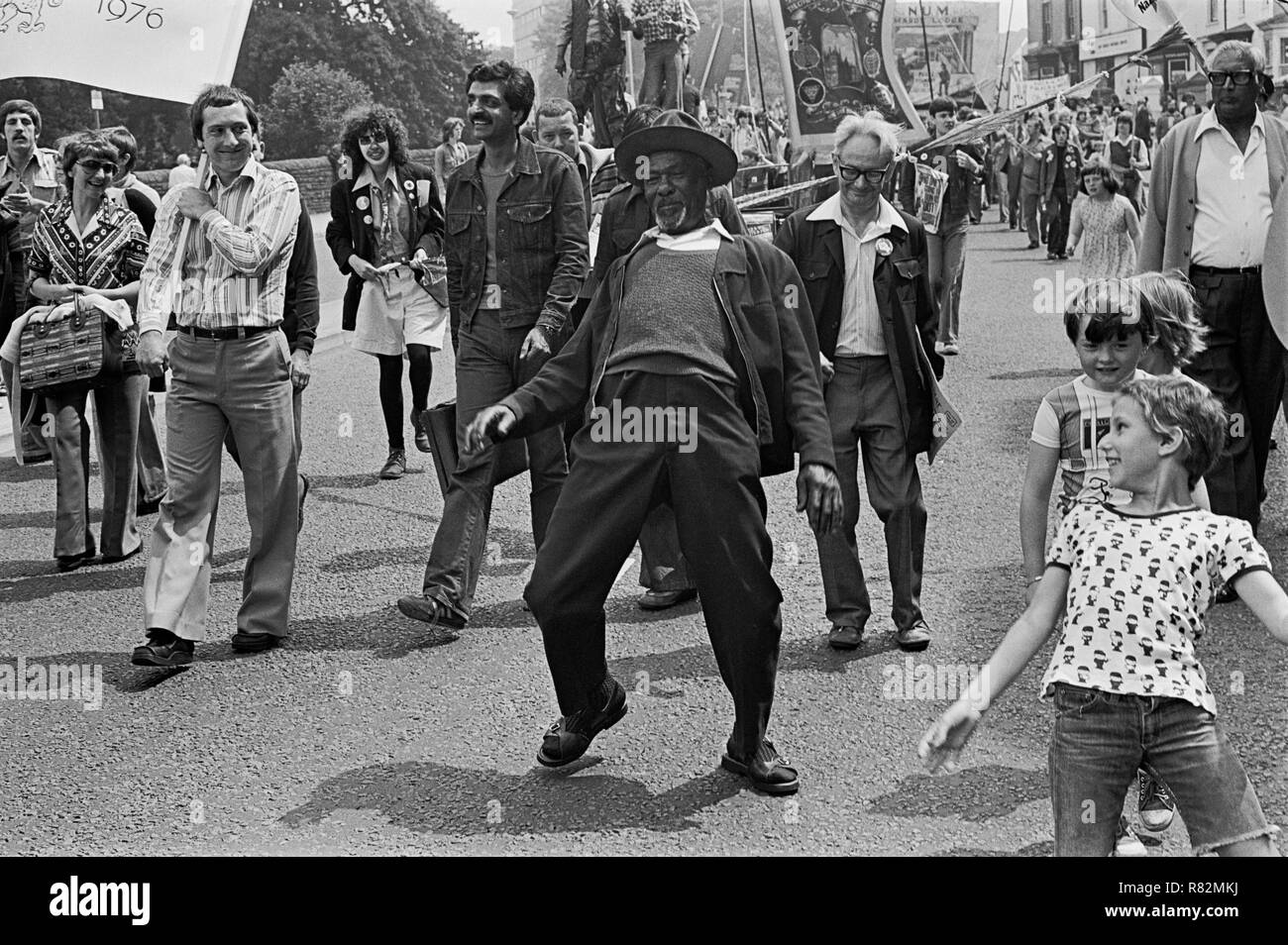 Un uomo danze giù la strada copiati dai bambini in una scherzosa momento in un anti-razzismo dimostrazione, Cardiff Wales, 1978. Foto Stock