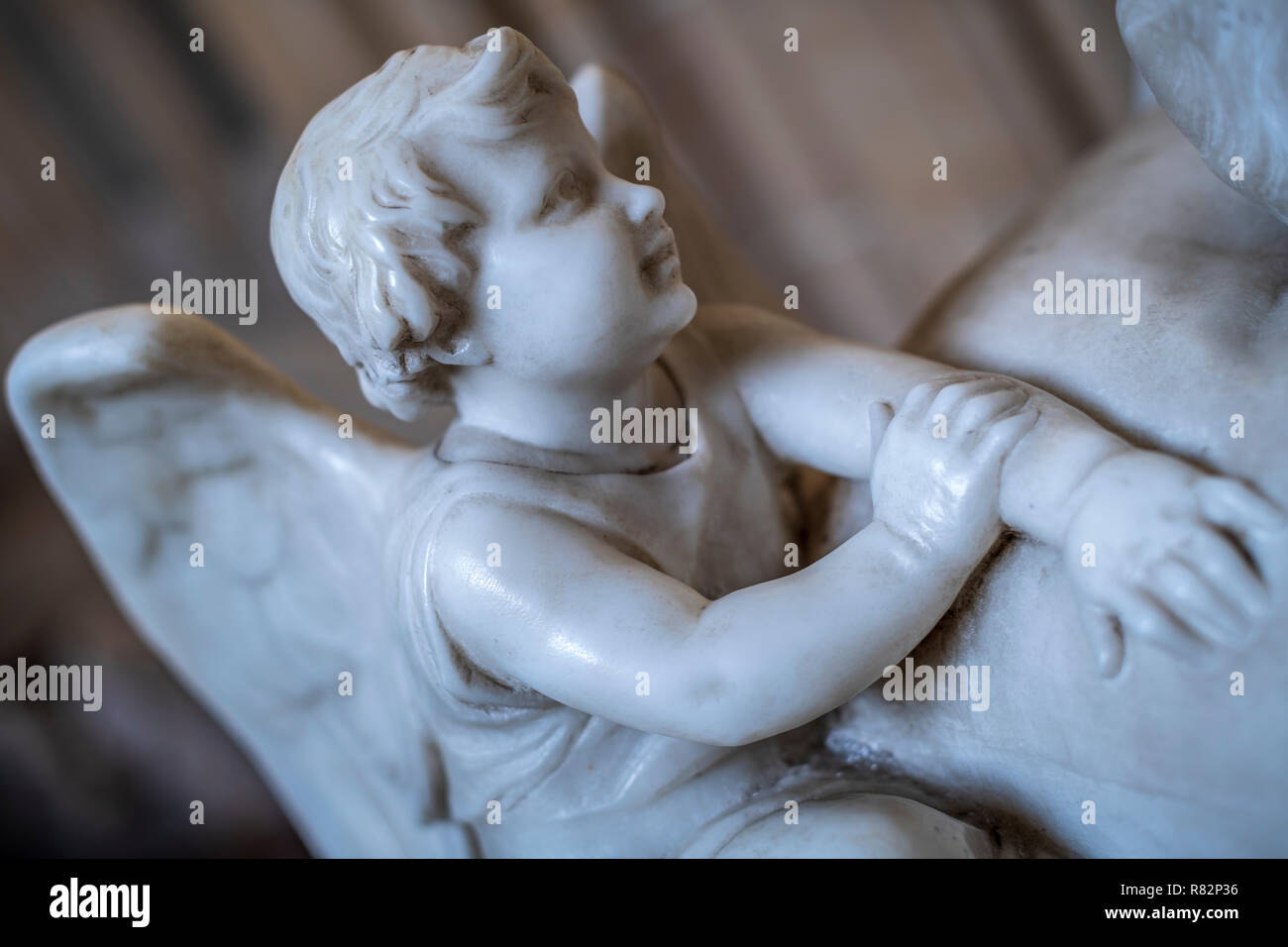 Un cherubino di marmo si trova a capo di una tomba nella Cattedrale di Wells, Somerset. Foto Stock