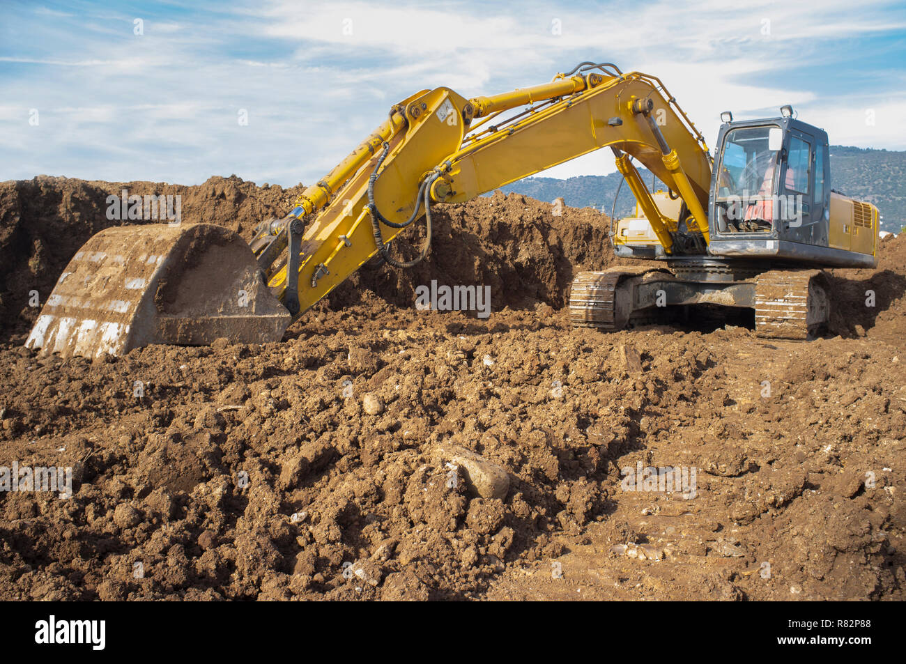 Escavatore per movimento terra preparando il cantiere per la costruzione del suolo. Bassa angolazione Foto Stock