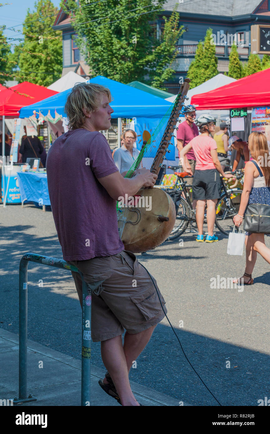 Portland, Oregon, Stati Uniti d'America - agosto 17,2014: Biancospino Street annuale evento comunitario. Un musicista di strada suona la Kora di uno strumento a corda. Foto Stock