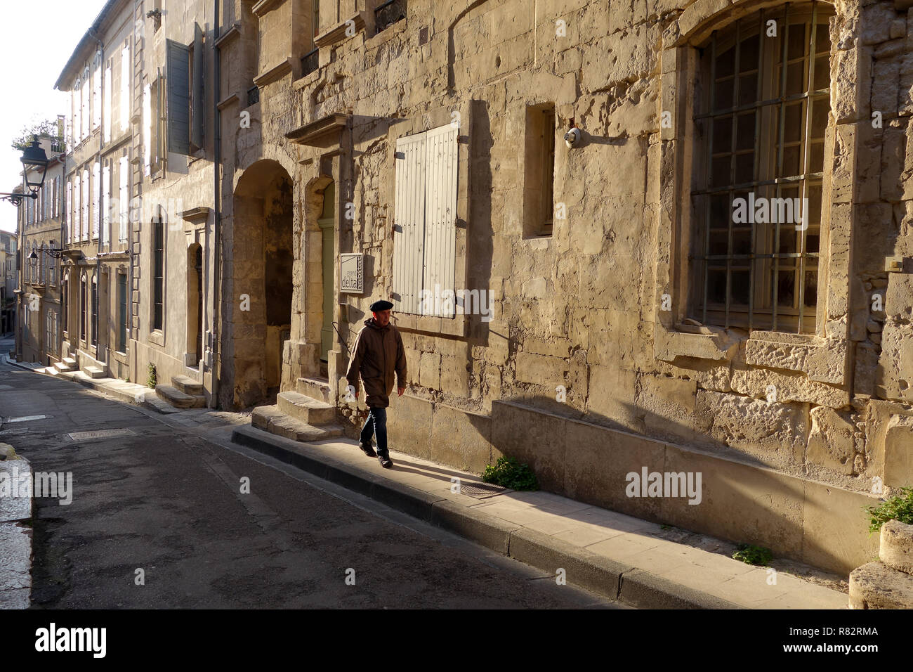 Lunghe ombre serali gettate da un uomo francese che indossa un berretto in Rue Des Arenes ad Arles in Francia Foto Stock